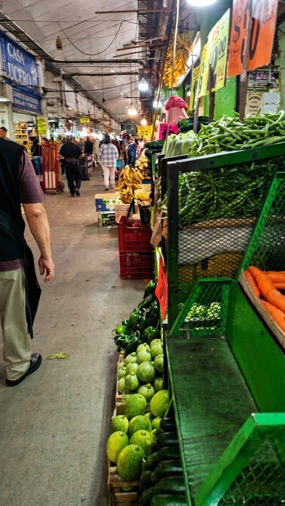 Pasillo de la Central de Abasto de la Ciudad de México con cajas de chile, calabaza, ejote y zanahoria